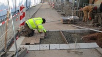 Zu sehen ist ein Bauarbeiter, der auf dem Pfarrer-Bleek-Platz neue Pflastersteine verlegt